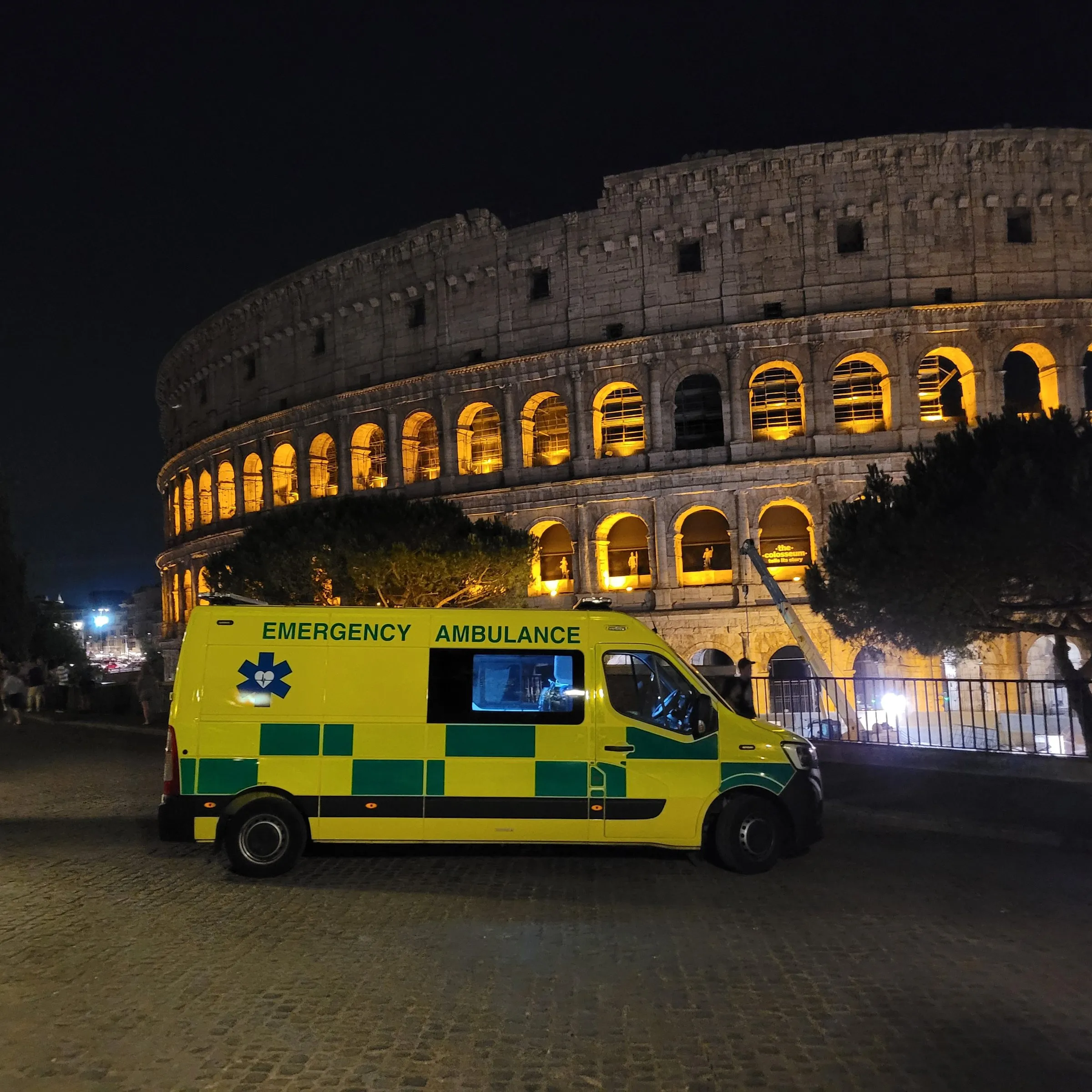A Hearts First ambulance parked at night in front of the illuminated Colosseum in Rome